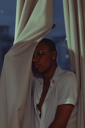 Man Standing Beside White Window Curtain