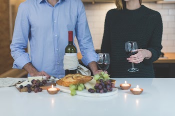 Man Standing Beside Woman in Front of White Wooden Dining Table
