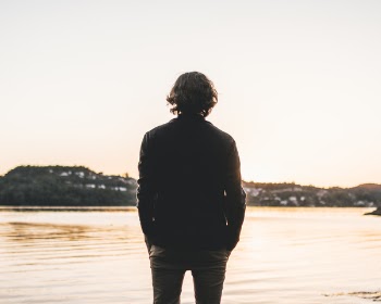 Man Standing Facing Body of Water