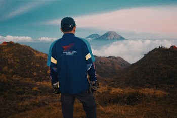Man Standing Facing the Mountain Above the Clouds