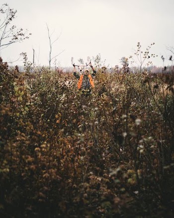 man standing grass under white sky