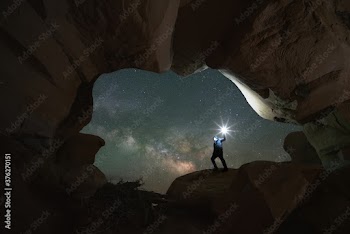 Man standing in a natural rock window in Devils Garden Escalante, Utah