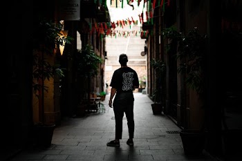 man standing in alley between buildings