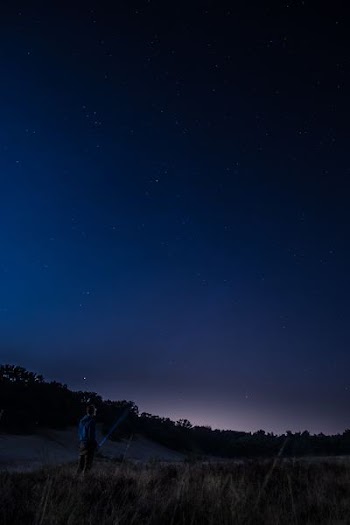 man standing in an open field at nighttime