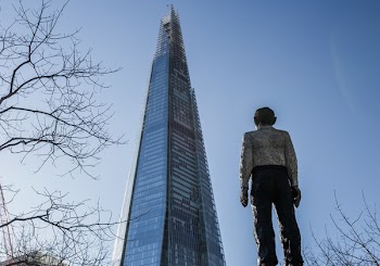 Man Standing in Front of a Sunrise Building Under Blue Sky