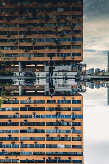 man standing in front of brown concrete high-rise building during daytime