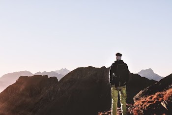 man standing in front of brown mountain scenery during daytime