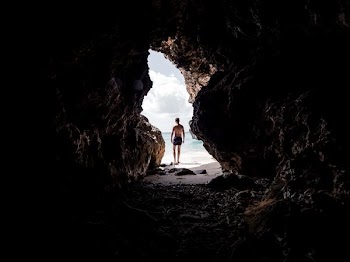 man standing in front of cave