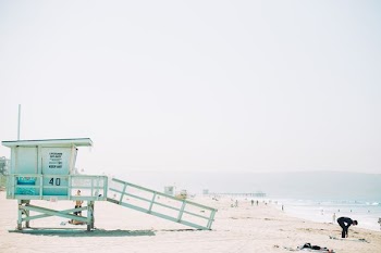 man standing in front of green wooden life guard station in seashore during day time