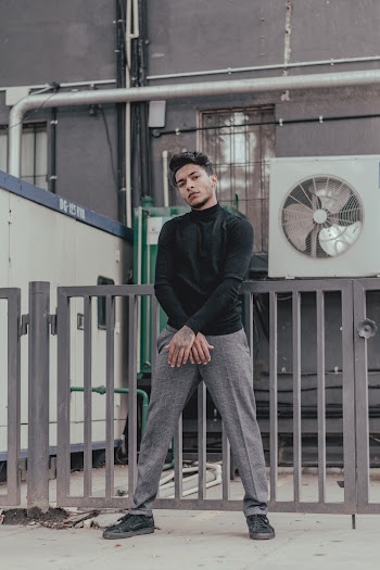Man Standing In front of Metal Fence