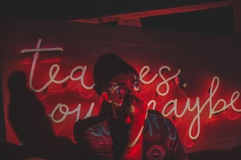 man standing in front of neon light signage in a dim lit room