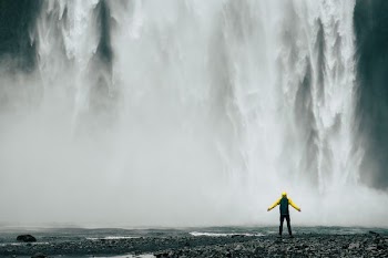 man standing in front of waterfalls at daytime