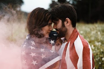 man standing in front of woman covered with U.S.A. flag