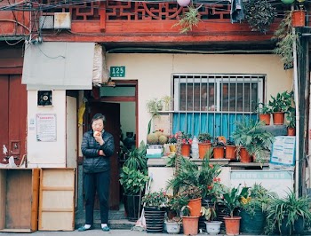man standing in ground door beside potted plants