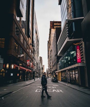 man standing in the middle of the road between buildings
