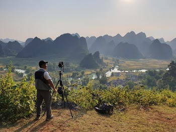 Man Standing Near Black Tripod Viewing Mountains