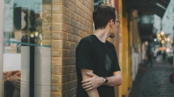 Man Standing Near Brick Wall