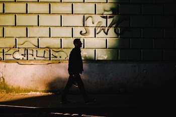 man standing near gray painted wall
