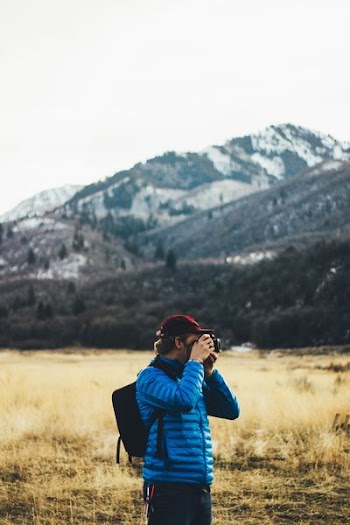 man standing near mountain taking photo
