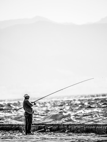 Man Standing Near Seashore Holding Fishing Rod on Grayscale Photography