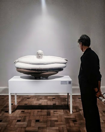 Man Standing Near Table Looking At An Artwork