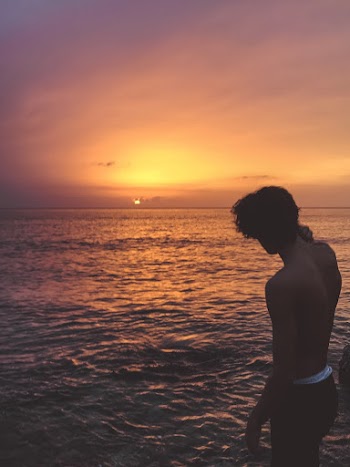Man  Standing Near the Body of Water during Golden Hour