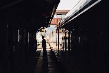 man standing near train in subway during daytime