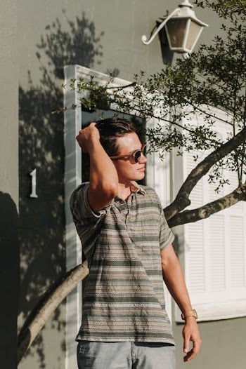 man standing near tree while holding his hair