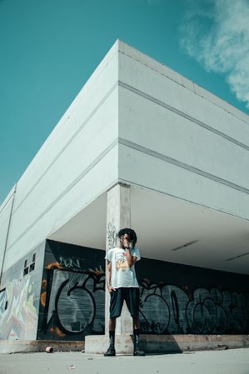 man standing near white post building under teal and white sky at daytime