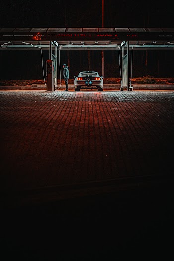 Man Standing next to a car at Gas  Station