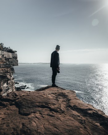 Man Standing on a Cliff Overlooking the Sea