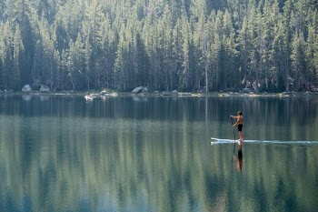 man standing on blue paddle board on body of water during daytime