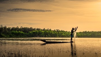 Man Standing on Boat While Fishing