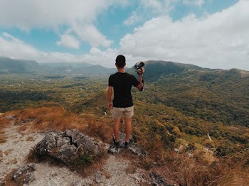 Man Standing On Brown Mountain Peak