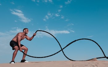 Man Standing on Brown Sand While Holding Black Rope