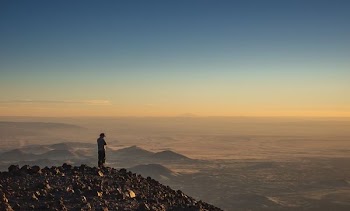 man standing on cliff during golden hour