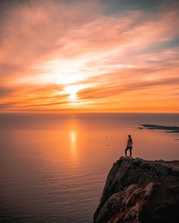 Man Standing On Cliff During Sunset