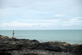 man standing on cliff fronting calm body of water