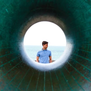 man standing on cliff near body of water