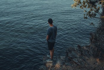 Man Standing on Cliff Near Body of Water