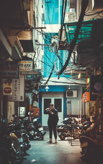 Man Standing on Concrete Road With Parked Motorcycles While Holding Dslr Camera