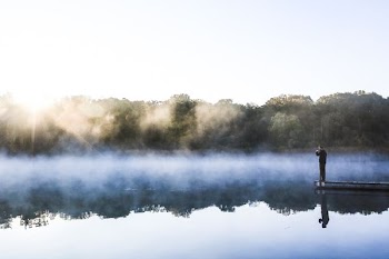 man standing on dock in front of water