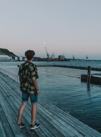 man standing on dock near sea
