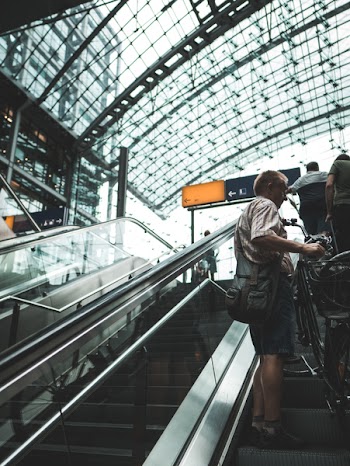 Man Standing On Escalator Holding Bike