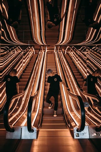 man standing on escalator with string lights