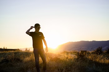 Man Standing on Grass Field Overlooking Sunrise