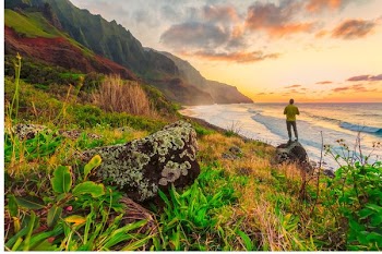 man standing on gray stand near sea and mountain range during daytime