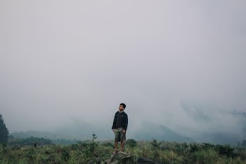 man standing on gray stone under cloudy sky