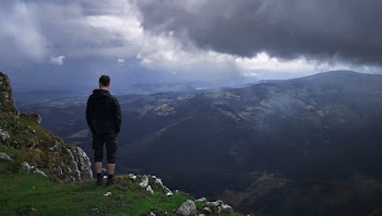 Man Standing on Green Grass Covered Mountain