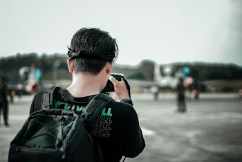 Man Standing on Grey Pavement While Taking Photo